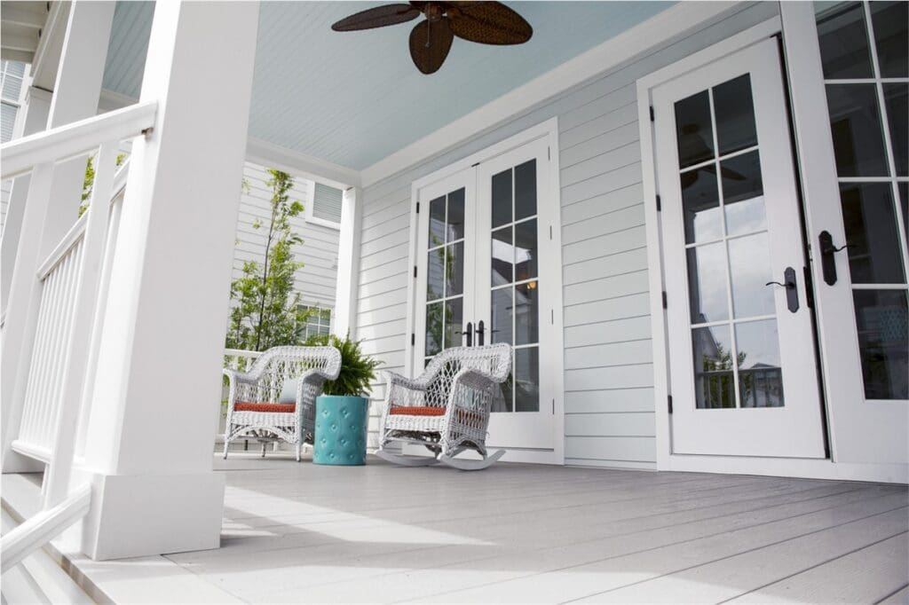 Serene home exterior featuring pristine white siding by HXHome Solutions, complemented by a new deck adorned with inviting outdoor chairs for a perfect blend of style and comfort.